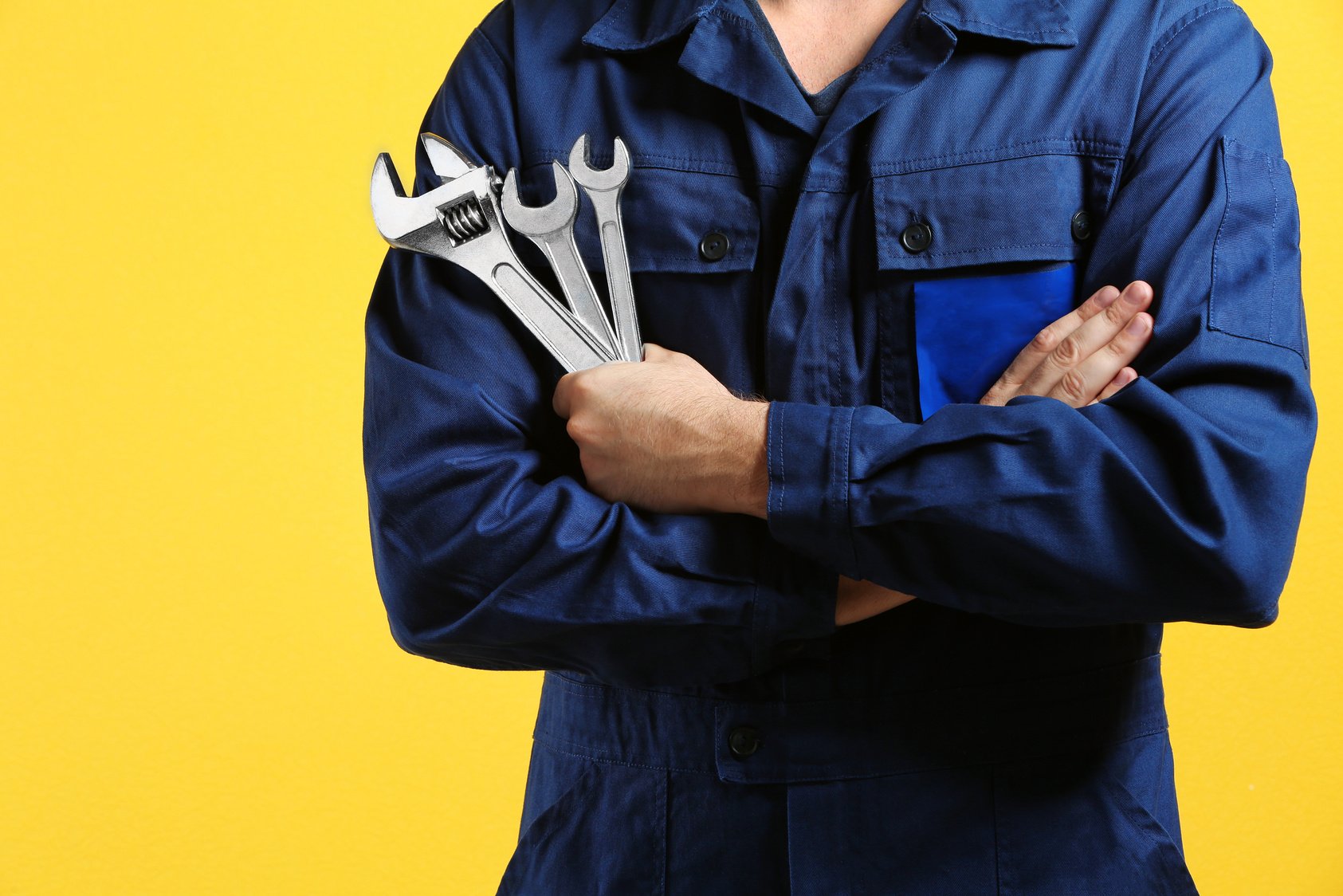 Mechanic with Crossed Arms and Wrenches 